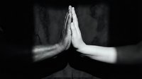 Two hands pressed together in prayer or meditation pose against dark background, symbolizing spirituality, mindfulness, gratitude, and inner peace for wellness and faith concepts.