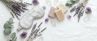 Spa wellness flat lay with lavender flowers, natural soap, eucalyptus leaves and amethyst crystals on white wooden background for relaxation.