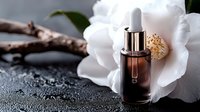 Luxurious skincare serum with dropper on white camellia flower against dark wet stone background. Elegant cosmetic product for beauty routine.