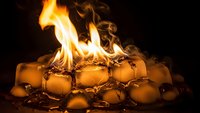 Burning ice cubes with dramatic flames and smoke creating surreal contrast between fire and frozen water elements on dark background.