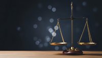 Golden scales of justice on wooden desk with bokeh background for legal services and law firm presentations.