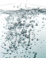 Clear bubbles rising through pure water create dynamic motion and texture, captured in high-speed photography against light background for freshness concepts.