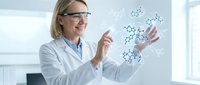 Female scientist in lab coat and safety glasses examining molecular structure model in modern laboratory for research and education.