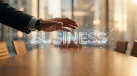 Businessman hand hovering over glowing holographic business text on conference table, digital innovation concept in modern office.