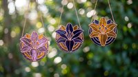 Colorful wooden leaf ornaments hanging on rope against blurred green foliage background. Handcrafted autumn decorations for seasonal home decor and crafting projects.