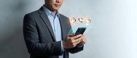Professional businessman in suit using smartphone with digital icons floating above device representing modern mobile technology and business communication.