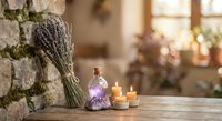 Dried lavender bundle with essential oil bottle and candles on rustic wooden table creating peaceful spa atmosphere for aromatherapy and relaxation.