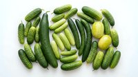 Fresh green cucumbers and pickles arranged on white background for healthy eating and food photography projects.