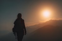 Silhouette of adventurous hiker with backpack standing on mountain peak during golden sunset, contemplating scenic landscape view for outdoor recreation.