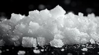 Macro shot of fresh snow crystals on dark background with selective focus showing delicate crystalline structure and natural winter texture.