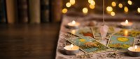 Mystical tarot cards spread on wooden table with glowing candles and warm bokeh lights creating atmospheric fortune telling scene for spiritual guidance.
