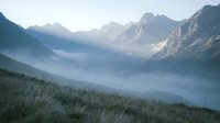 Misty mountain valley at dawn with layered peaks, forested slopes, and fog-filled basin creating atmospheric landscape scenery for nature and travel projects.
