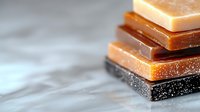 Stacked chocolate bars in different shades from dark to milk and white chocolate on blurred gray background, macro shot with selective focus and copy space.