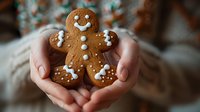 Hands holding homemade gingerbread man cookie with white icing decoration, festive holiday baking tradition for Christmas celebrations.
