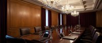 Elegant corporate boardroom with polished wood paneling, crystal chandeliers, and leather executive chairs around mahogany conference table for business meetings.