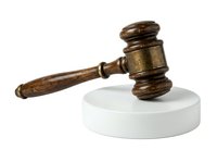 Wooden judge gavel with brass band resting on white circular base, symbolizing law, justice, court decisions, and legal authority for litigation and judicial proceedings.
