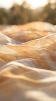 Sheer golden fabric with soft folds and waves catching warm sunlight, creating elegant textures and shadows. Suitable for fashion, textile, and lifestyle design projects.