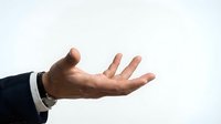 Male hand in open palm gesture wearing dark business suit with white shirt cuff against neutral background, conveying offering, acceptance, or negotiation concepts for corporate communications.