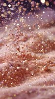 Abstract rose gold glitter particles floating against blurred background with bokeh lights, creating magical festive atmosphere.
