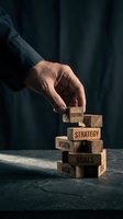 Hand stacking wooden blocks labeled future, strategy, vision, goals and risk, symbolizing business planning and leadership on dark background.