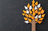 Stylized wooden tree with orange and white paper leaves on dark background, creative minimal paper craft design concept for education and growth.