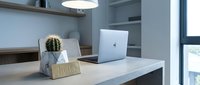 Modern home office desk with laptop, cactus plant, and hello sign under pendant light, minimalist Scandinavian interior design workspace.