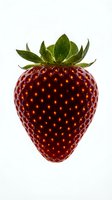 Fresh ripe strawberry with green leafy crown isolated on white background. Vibrant red fruit with detailed seeds, ready for food, nutrition, and healthy eating design projects.