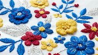 Colorful embroidered flowers with blue, yellow and red blooms on white fabric. Traditional needlework craft with decorative stitching for textile design projects.