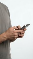 Man wearing gray casual shirt holding smartphone, isolated on white background for app, technology, communication, and mobile device concepts.