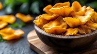 Fresh golden chanterelle mushrooms in rustic wooden bowl on cutting board, organic forest fungi harvest ready for gourmet cooking and culinary preparation.