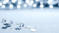 Clear water droplets scattered on clean white surface with soft bokeh lights creating elegant minimalist background for product photography and design.