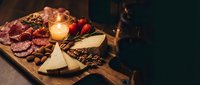 Gourmet charcuterie board with assorted meats, artisan cheeses, nuts and berries arranged on wooden platter with warm candlelight for entertaining.