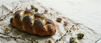 Golden braided challah bread with sesame seeds on rustic linen cloth, traditional Jewish bakery loaf for holidays and celebrations, artisan homemade baking.