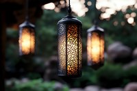 Glowing oriental lanterns with intricate patterns casting warm light in garden setting at dusk, creating magical ambiance for outdoor decoration and events.