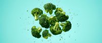 Fresh broccoli florets suspended in mid-air against turquoise background, ideal for healthy eating, nutrition, organic food, and vegetarian cooking content.