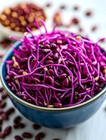 Fresh purple bean sprouts in blue ceramic bowl, close-up view showing vibrant color and delicate tendrils against white background, raw organic microgreens for healthy eating.