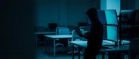 Young professional man working late at night in dark office with glowing computer screen, overtime concept for business and technology projects.