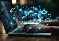 Cloud computing concept with glowing cloud icons and digital data streams floating above laptop keyboard in dark office environment with bokeh lights.