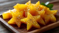Fresh ripe mango slices arranged on wooden plate with sesame seeds garnish, tropical fruit dessert ready for healthy snacking and culinary presentations.
