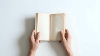 Hands holding open blank book with empty pages on white background, ready for text or design content, mockup template for publishing projects.