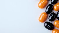 Orange and black capsule pills arranged on white background, pharmaceutical medication concept for healthcare and treatment options.