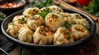 Pan-fried dumplings garnished with fresh herbs and chili sauce on dark plate, close up view of traditional Asian cuisine with golden crispy bottom.
