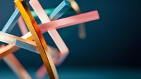 Colorful wooden sticks arranged in abstract geometric composition against dark background, creating dynamic intersecting lines and modern minimalist art pattern.