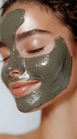 Young woman with medium skin tone applying olive green clay mask treatment to face for skincare and beauty routine, spa wellness and facial care.