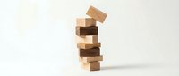 Wooden blocks tower falling down on white background. Business concept of instability, risk management and strategic planning challenges.