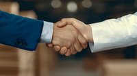 Business professionals shaking hands in agreement, symbolizing partnership, deal closing, and successful negotiation in corporate environment.
