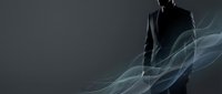 Silhouetted male professional in dark suit stands against gray background with flowing blue-green abstract light waves and smoke effects, conveying modern business innovation and corporate transformation.