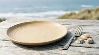 Empty wooden plate with fork and seashells on rustic weathered table outdoors, coastal dining and seaside restaurant concept for hospitality and food service design.