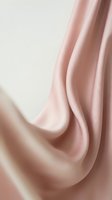 Soft pink silk fabric with elegant flowing drapes and smooth texture creating luxurious waves and folds for fashion and textile design backgrounds.