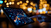 Person analyzing financial data on tablet with colorful charts and graphs against blurred city lights background at night.